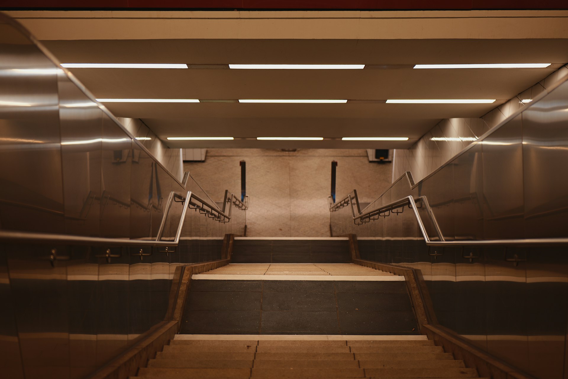 A modern subway station staircase with bright lights.